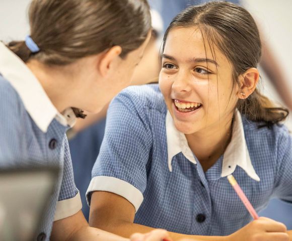 Two students talking and laughing together in the classroom