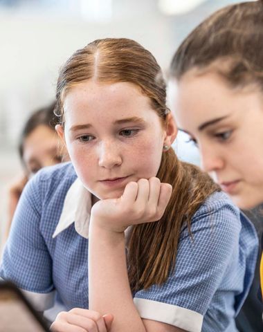 Two students working together on a laptop in the classroom