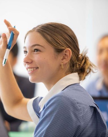 A Senior School student with her hand up in class