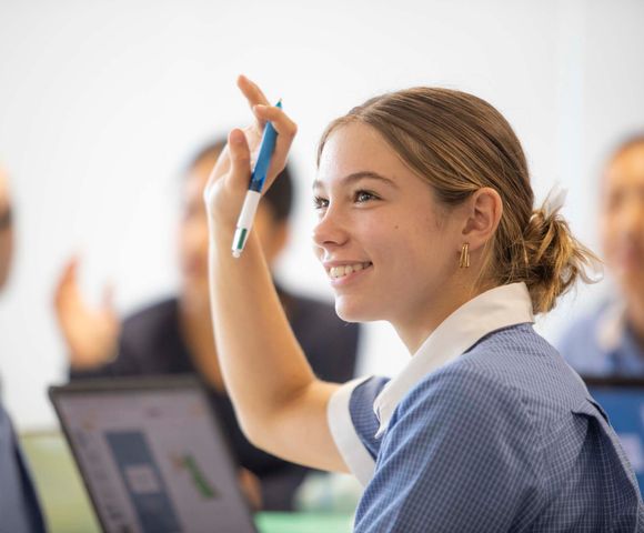 A Senior School student with her hand up in class