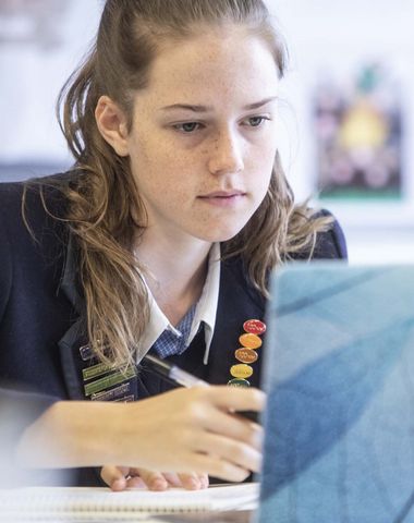 Student engaged in her school work and laptop in the classroom