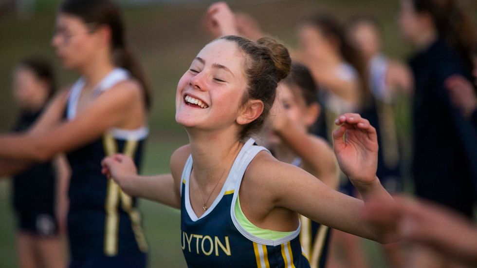 student smiling as she warms up before running.