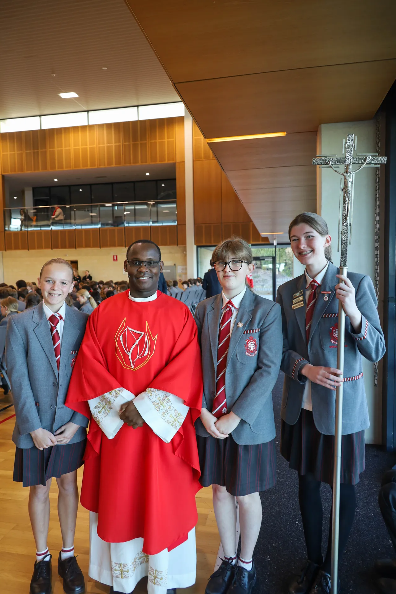 Students and a Priest holding a Crucifix before Mass