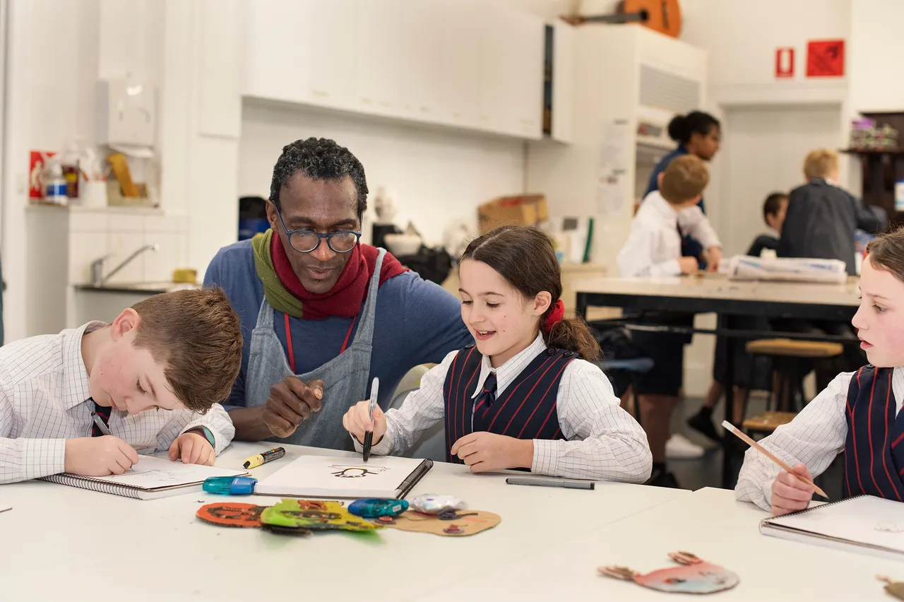 Teacher supports students with painting tips during class.