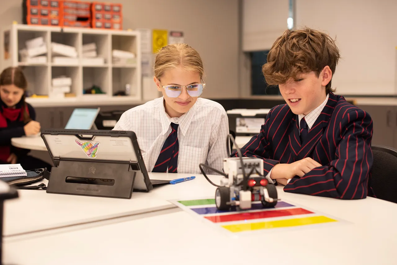 Two students in classroom looking at a robot during Science class.