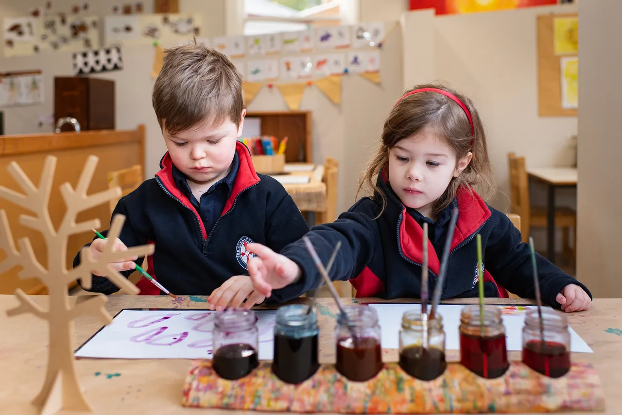 Two St Michael's Grammar School ELC students concentrate on a painting activity.