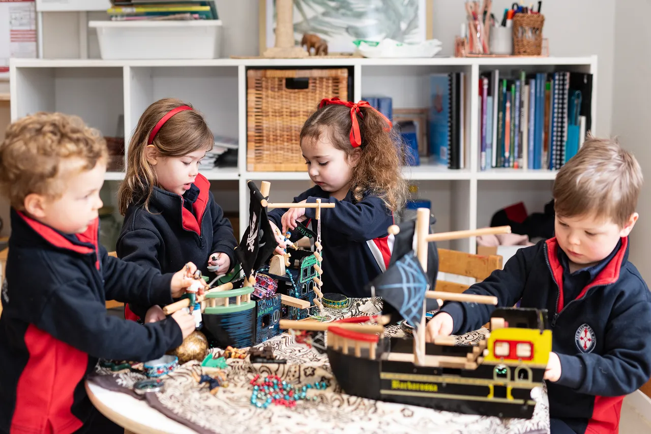 Four St Michael's Grammar School ELC students engage in imaginative play with a collection of props and loose materials in their early learning classroom.