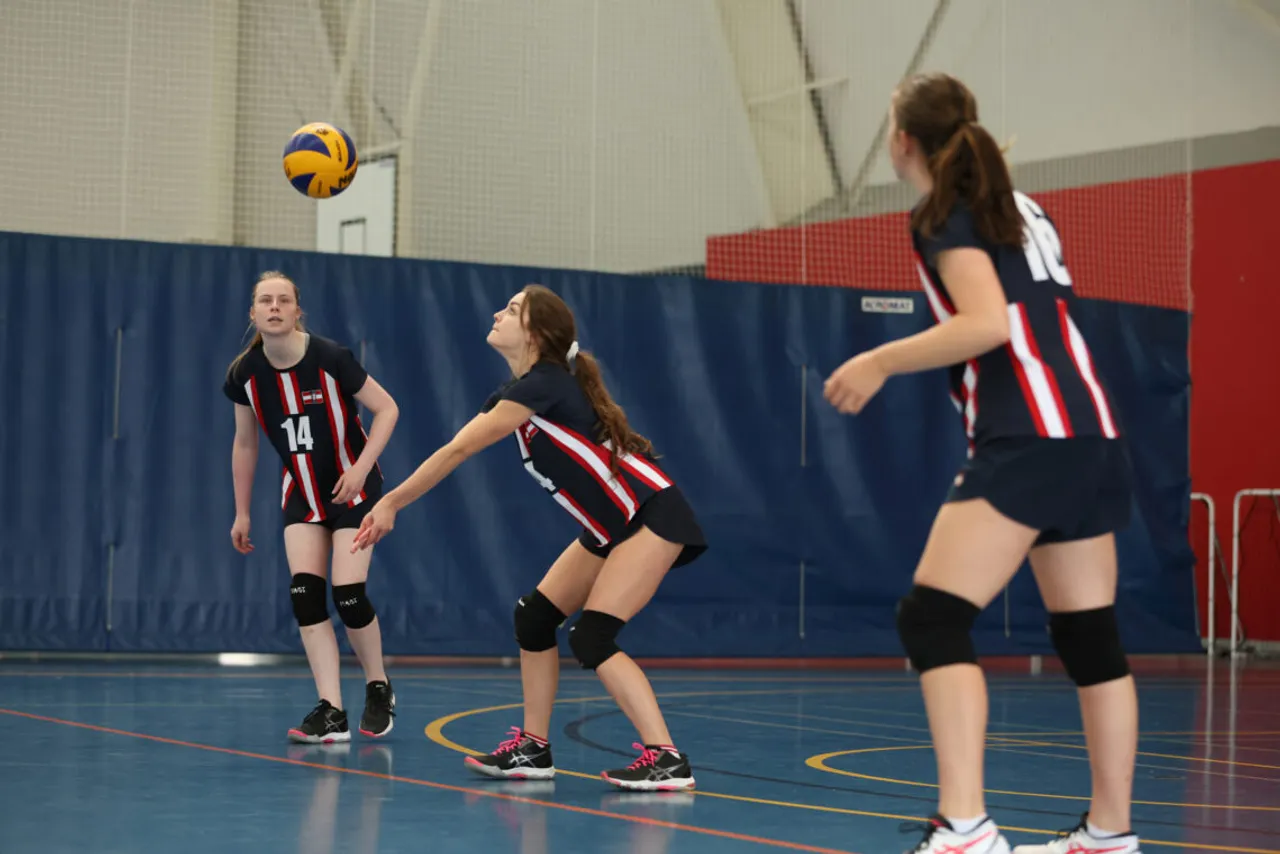 St Michael's Grammar School students in sport uniform compete in a volleyball match in an indoor gymnasium.
