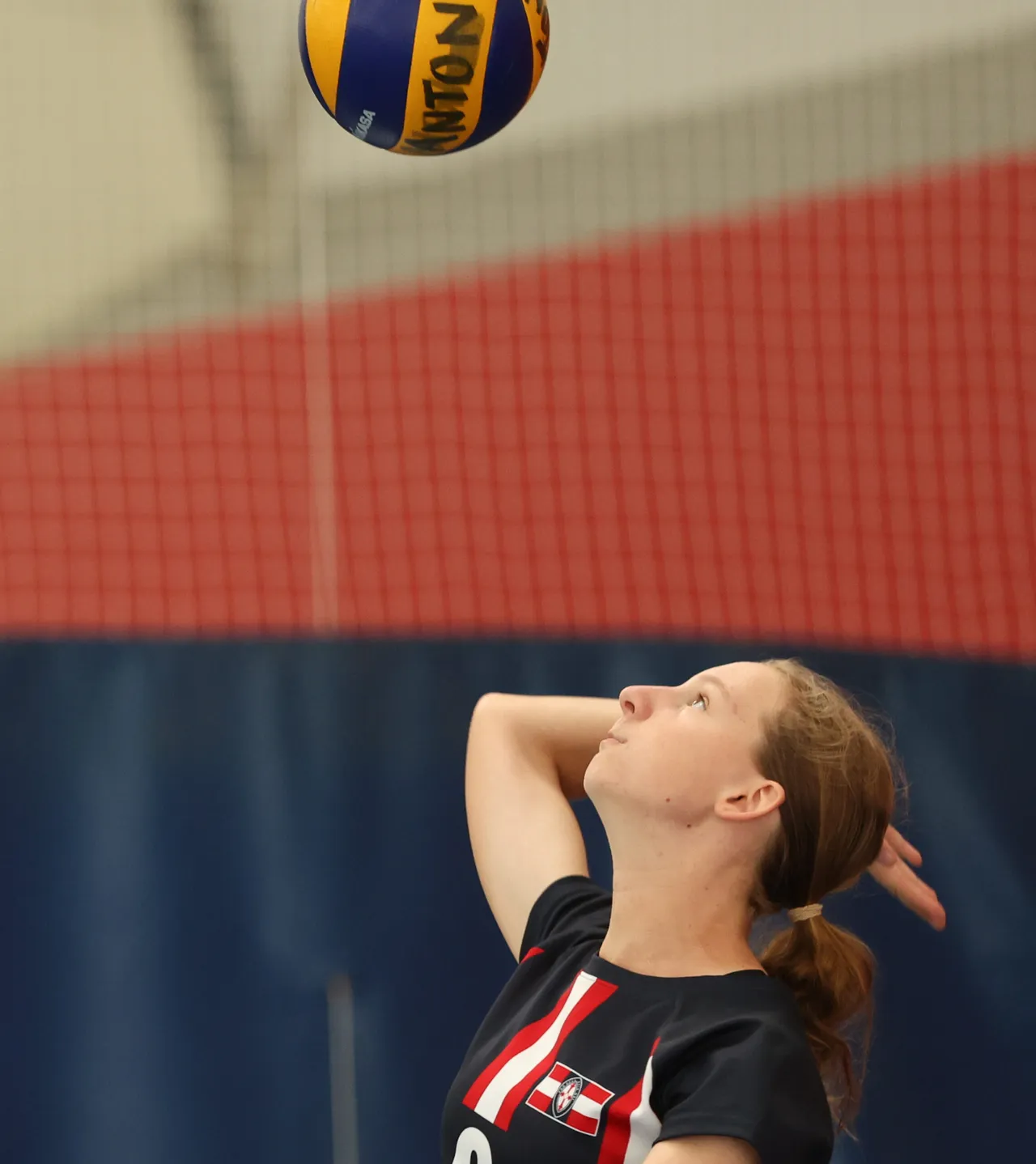 A St Michael's Grammar School student prepares to serve during a volleyball match in the school's indoor gymnasium.