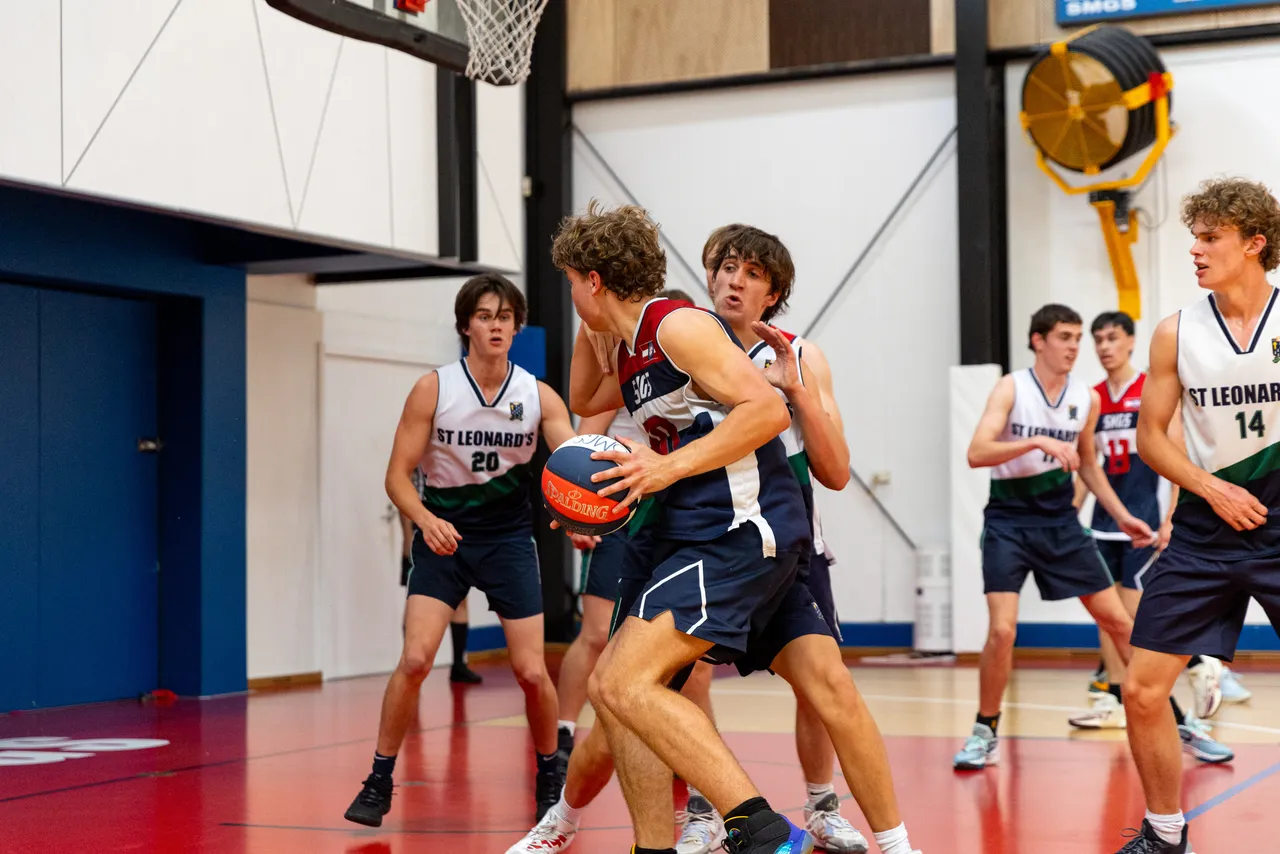 St Michael's Grammar School students compete in an interschool basketball match in an indoor gymnasium.