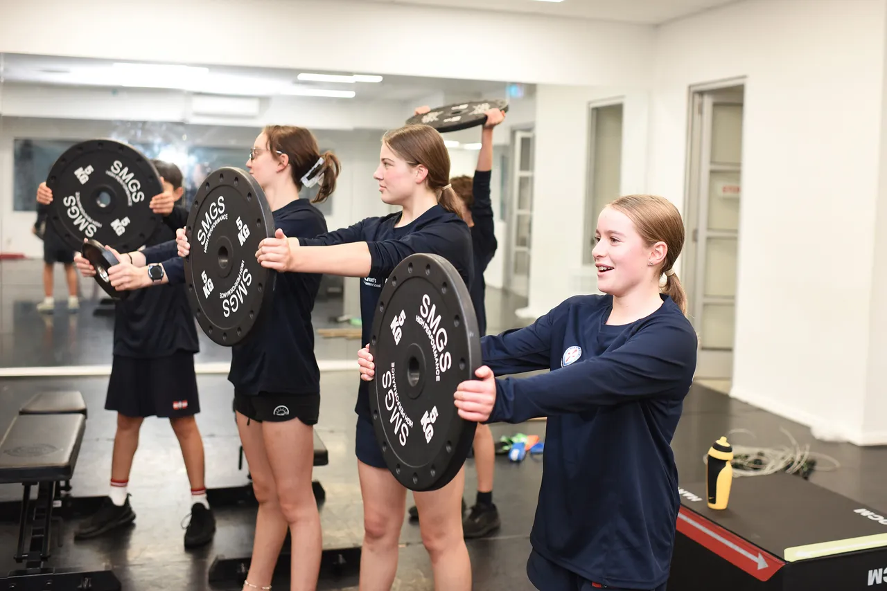 St Michael's Grammar School students lift weighted barbells during a strength training session in the school's gymnasium.