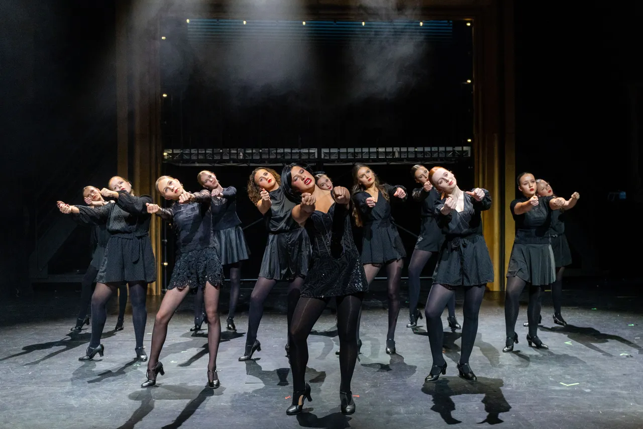 A group of St Michael's Grammar School students perform a choreographed dance routine on stage during a school production.