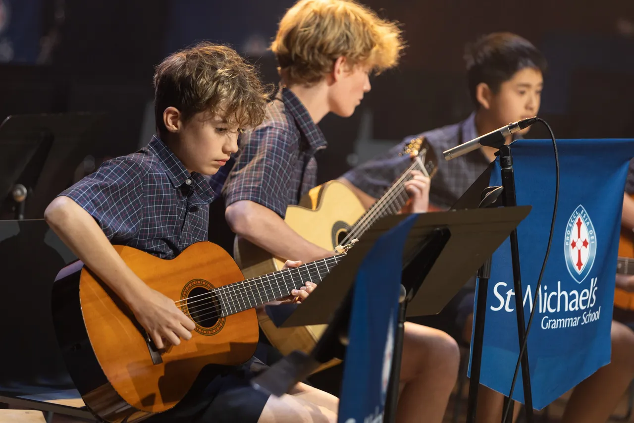 St Michael's Grammar School students play guitar together during a music class or ensemble rehearsal.