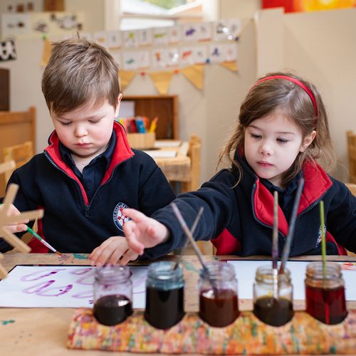 Two St Michael's Grammar School ELC students concentrate on a painting activity.