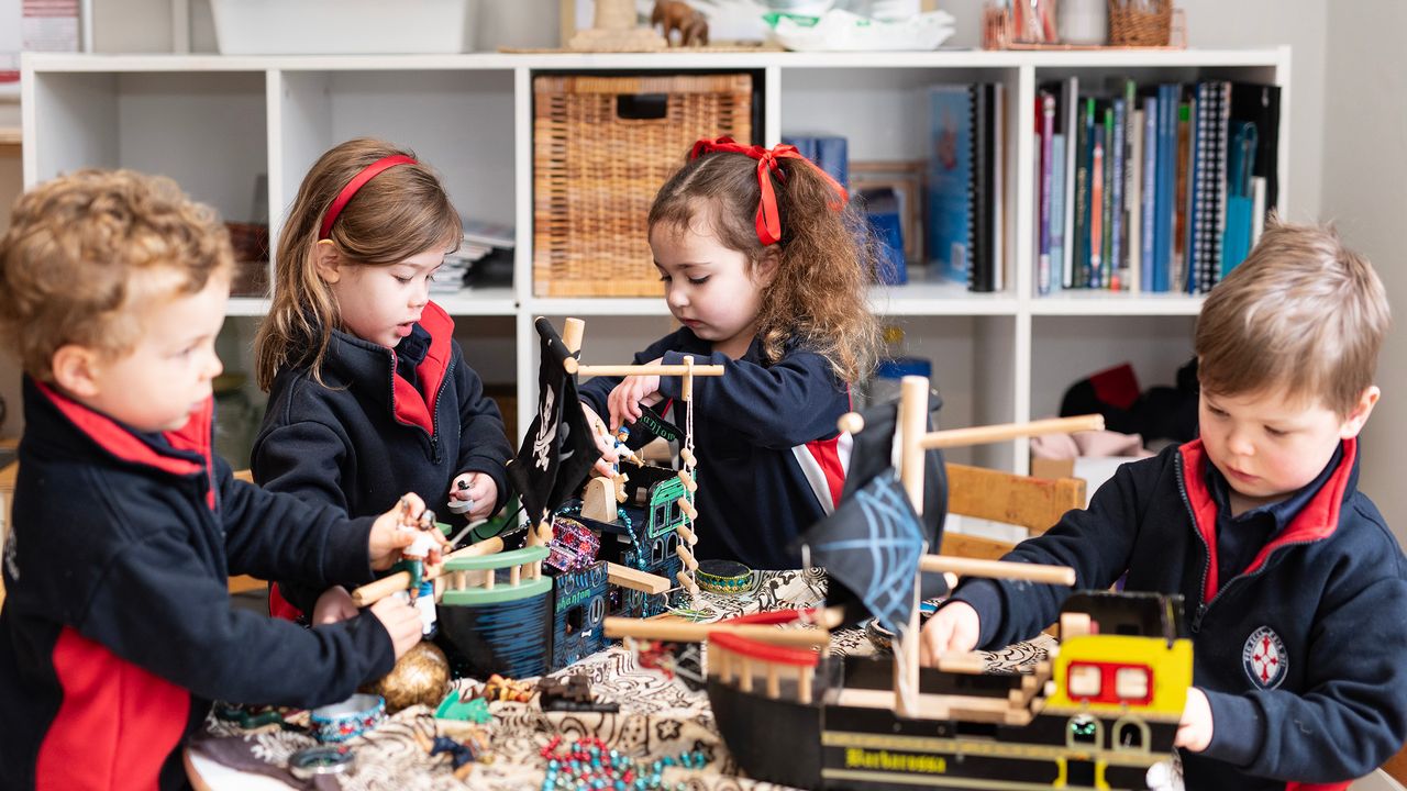 Four St Michael's Grammar School ELC students engage in imaginative play with a collection of props and loose materials in their early learning classroom.