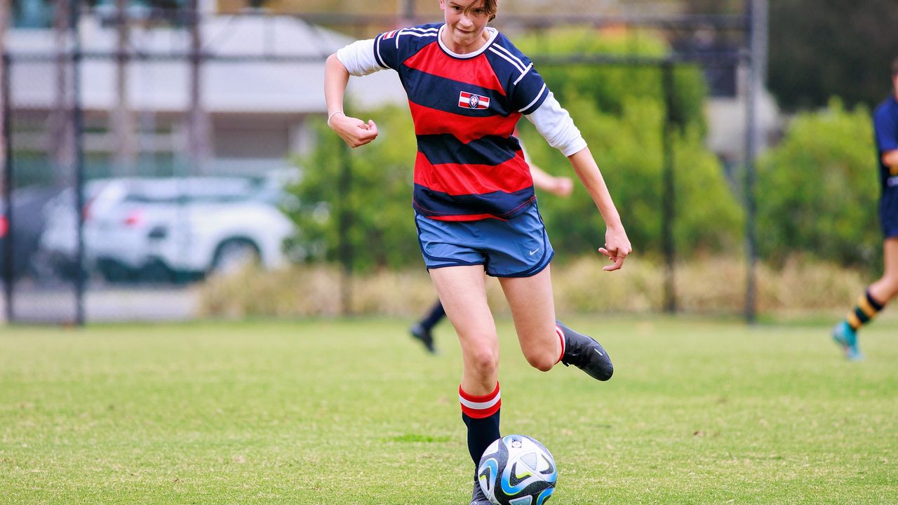 A St Michael's Grammar School student breaks forward with the ball during an outdoor soccer match.