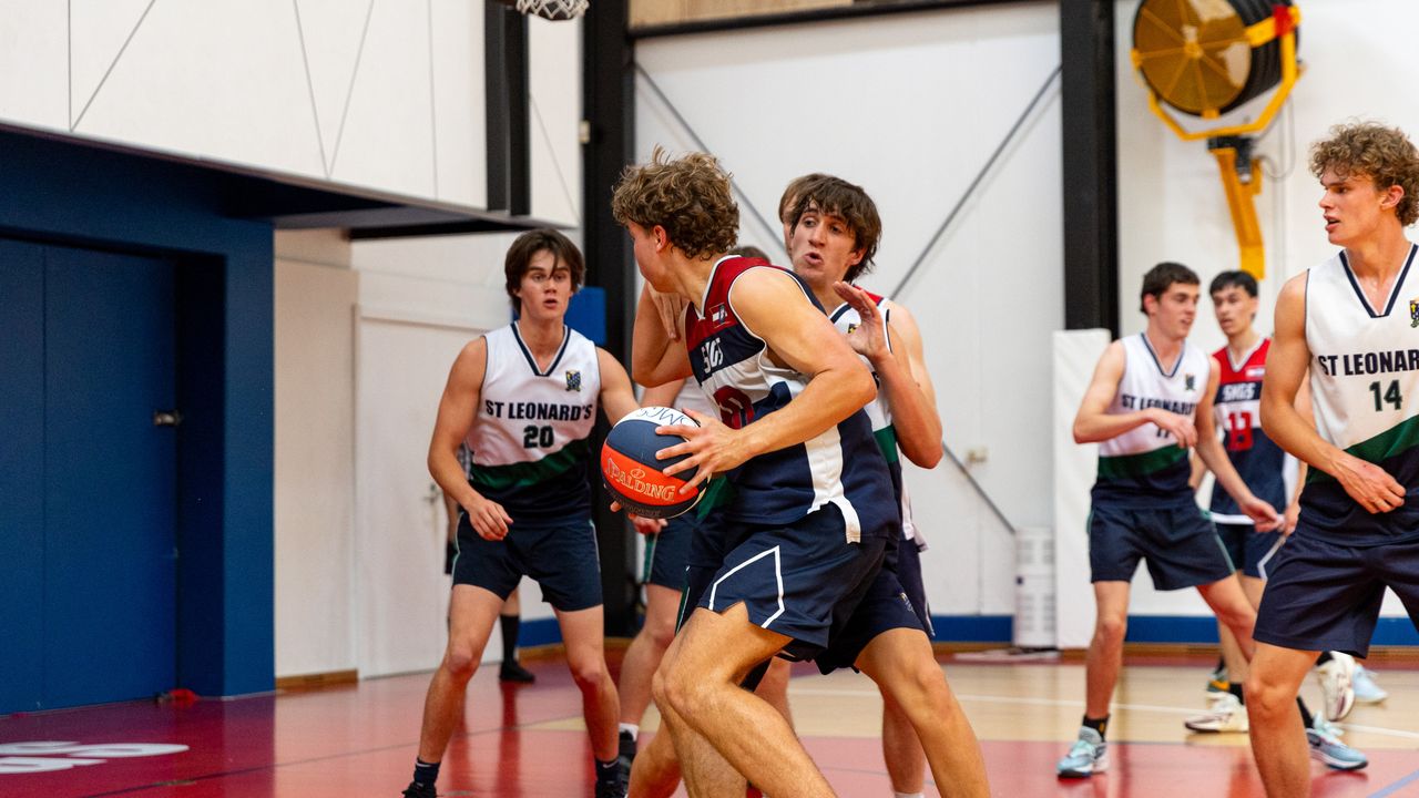 St Michael's Grammar School students compete in an interschool basketball match in an indoor gymnasium.